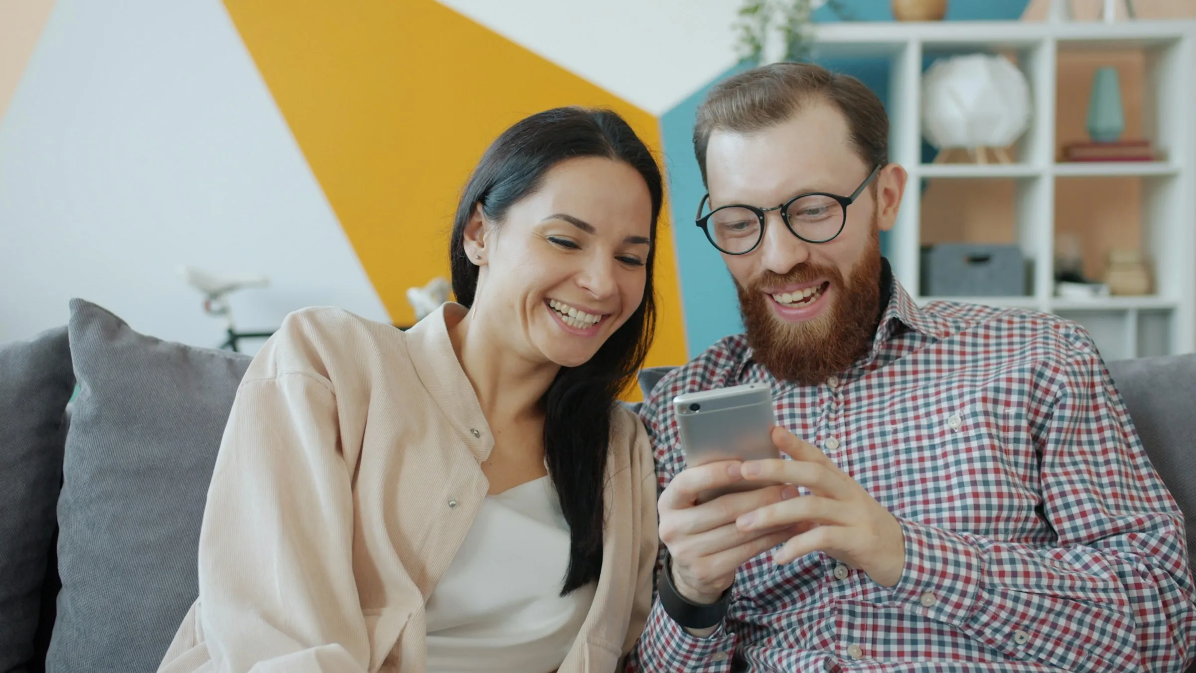 Couple laughing together while looking at a smartphone